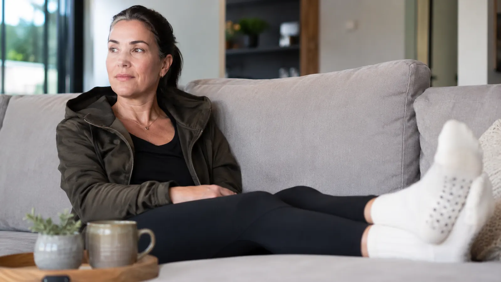Woman foam rolling tight calves on a kitchen floor between errands