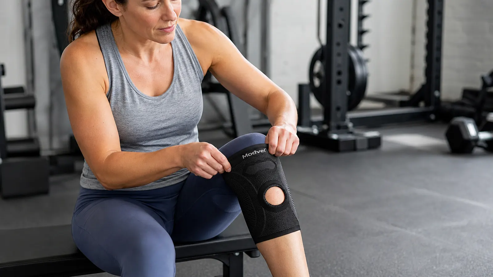 Close-up of the Modvel compression knee brace being pulled on over bare skin, silicone grip band visible